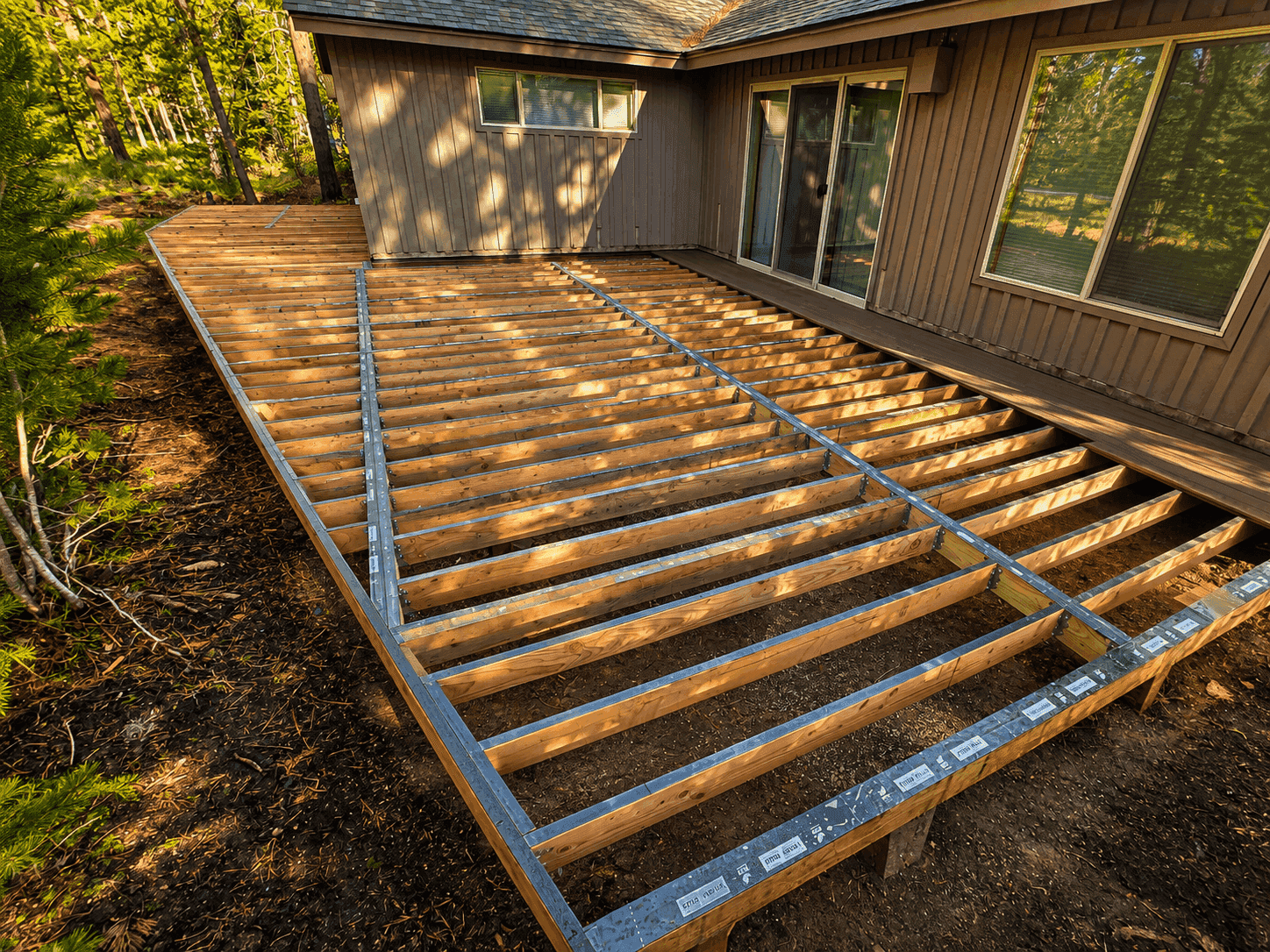 Deck framing under construction, joists and beams visible before decking installation